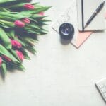 Biurko z tulipanami, aparatem retro i eleganckimi przyborami do pisania