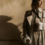 Kobieta w beżowym trenczu Burberry pozuje w jesiennym słońcu