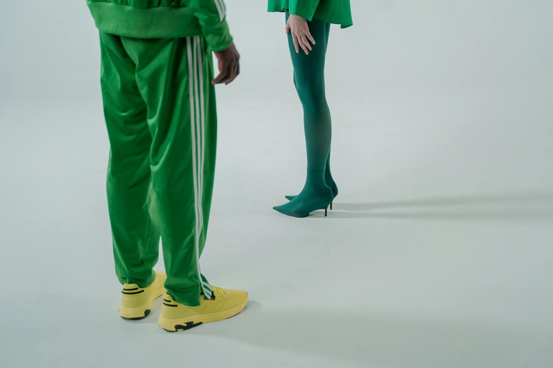 Kobieta w zielonym dresie Adidas i szpilkach pokazuje modny miejski look