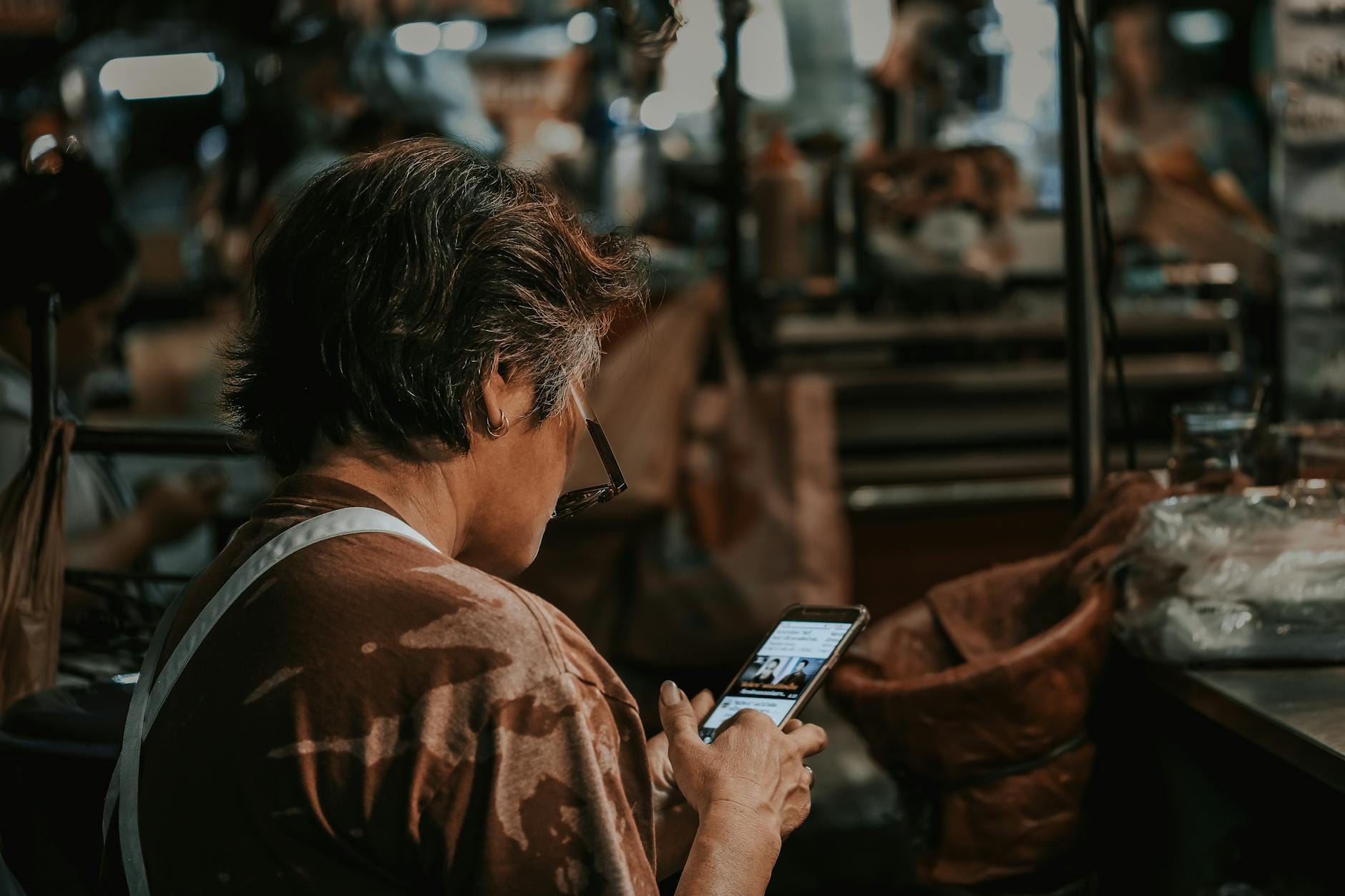 Kobieta z krótkimi włosami sprawdza ofertę Chanel na telefonie na targu