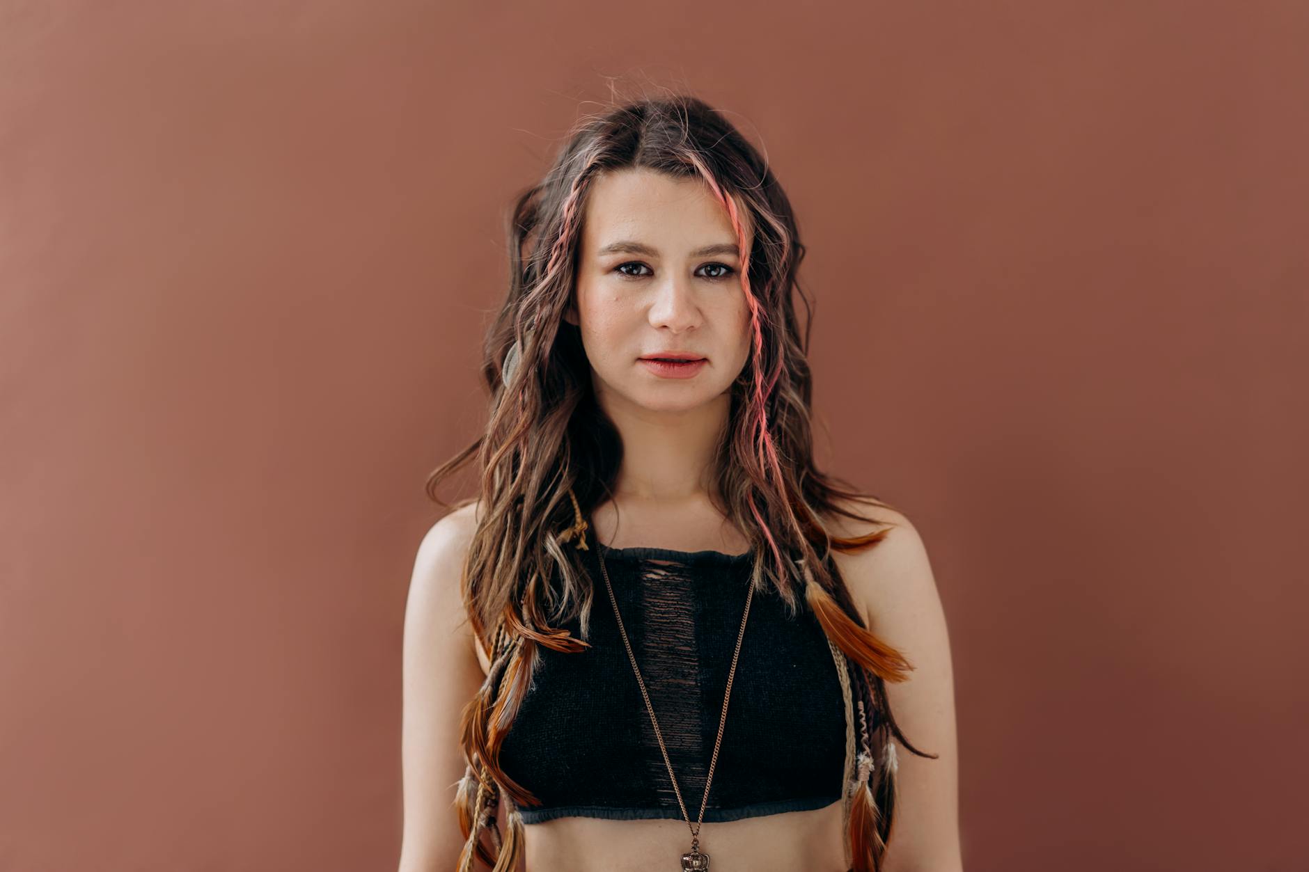 Zara i trendy: jak marka wyłapuje hity szybciej niż konkurencja? Młoda kobieta w kolorowych włosach w modnym topie na brązowym tle