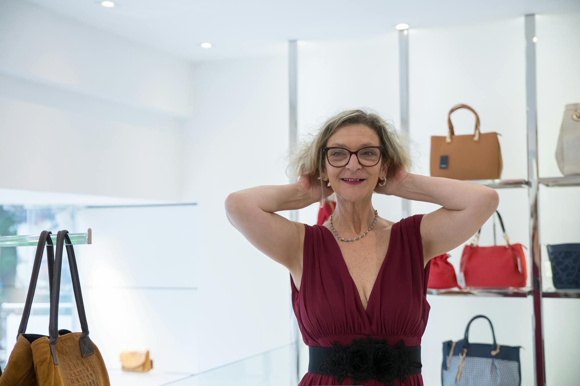 Starsza kobieta w eleganckiej sukience w butiku z markowymi torebkami