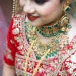 Zbliżenie na pannę młodą w czerwonej sari z bogatą biżuterią Dior